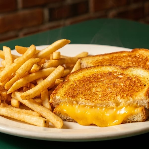 A plate of golden grilled cheese with melted cheddar and a side of crispy french fries.